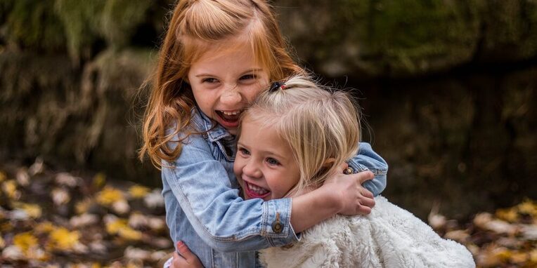 Zwei junge Mädchen lachen und umarmen sich