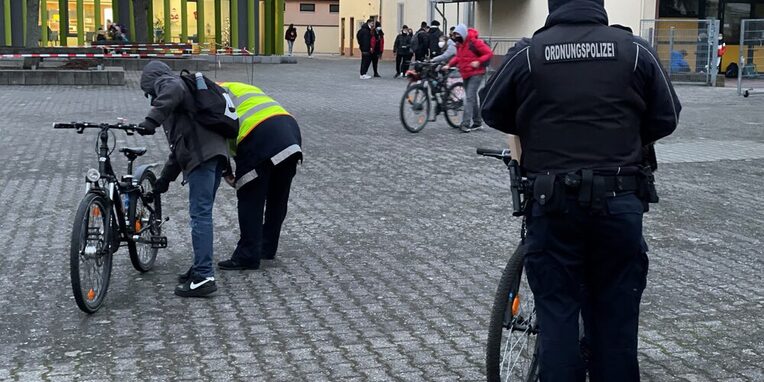 Ordnungspolizei überprüft auf dem Schulhof die Fahrradbeleuchtung