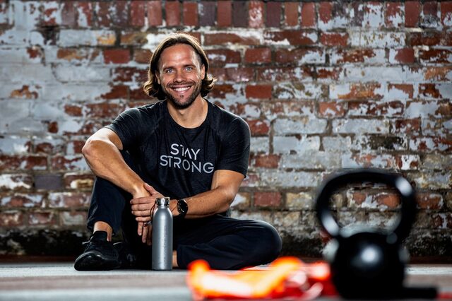 Timo Gudrich auf dem Boden sitzend mit einer Trinkflasche vor einer Steinwand