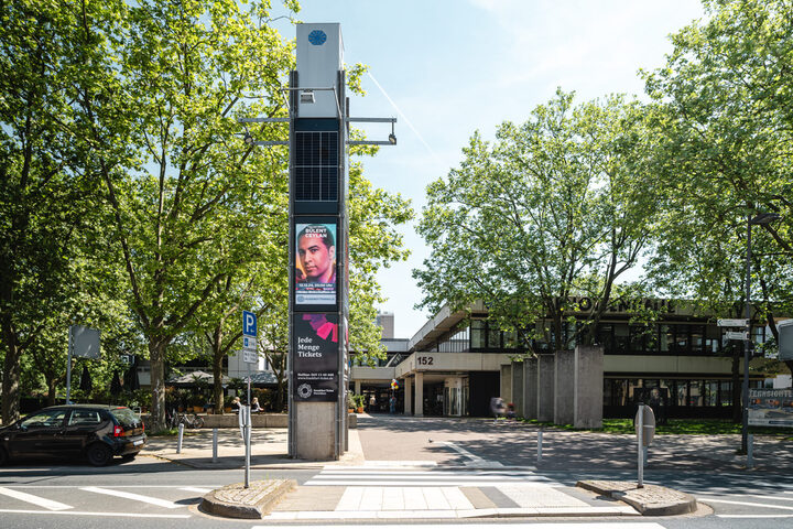 Blick auf die Hugenottenhalle und Stadtbibliothek im Vordergrund die digitale Infosäule