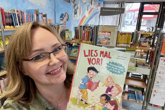 Linda Hein hält ein Buch in der Hand in der Stadtbibliothek