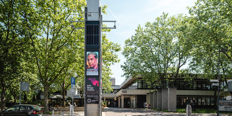Blick auf die Hugenottenhalle und Stadtbibliothek mit der digitalen Infosäule im Vordergrund