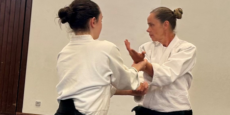 Aikido Ferienspiele 2025 zwei Frauen,in schwarz-weißer Kleidung auf einer blauen Gymnastikmatte