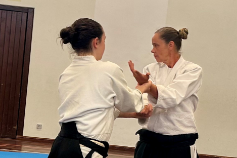 Aikido Ferienspiele 2025 zwei Frauen,in schwarz-weißer Kleidung auf einer blauen Gymnastikmatte