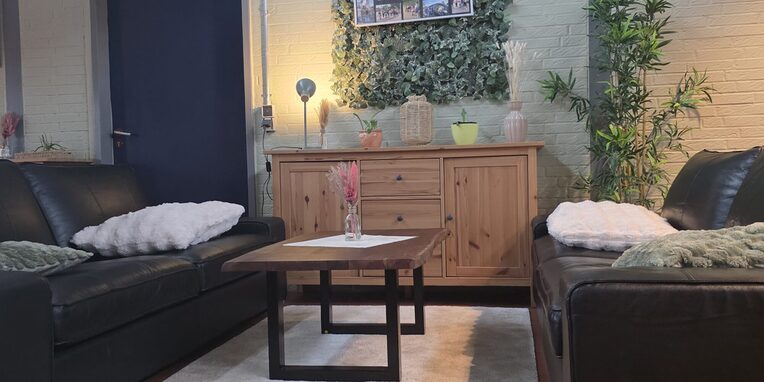 Neu gestaltetes Ambiente des Jugendraums  mit schwarzen Ledersofas, Tisch und einem Sideboard