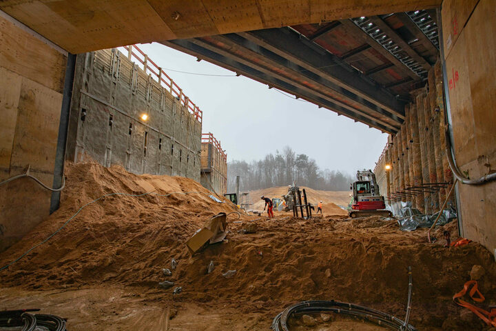 Tunneldurchstich Regionaltangente West am Kreuzungsbauwerk Neu-Isenburg, Blick aus dem Tunnel mit Sandhügeln, Baugeräten und Arbeitern