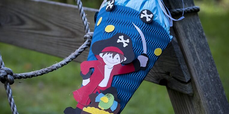 Blaue Schultüte mit roten Piraten dekoriert anlehnend an einer Holzkonstruktion