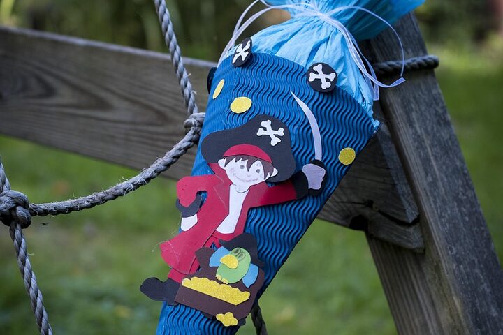 Blaue Schultüte mit roten Piraten dekoriert anlehnend an einer Holzkonstruktion