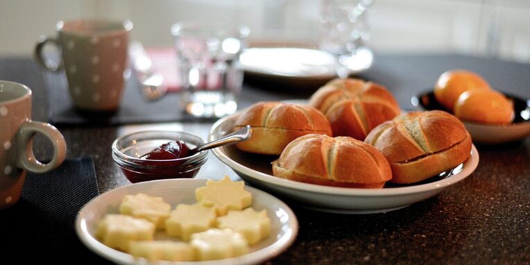 Frühstückstisch mit Brötchen, Butter, Marmelade und Eier