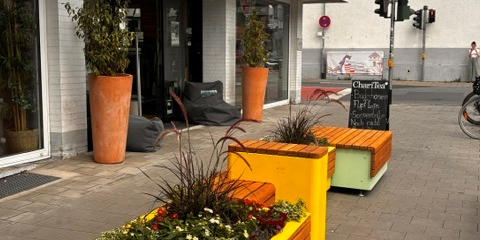 orangefarbene Sitzmöglichkeit auf der Frankfurter Straße mit Pflanzgefäßen