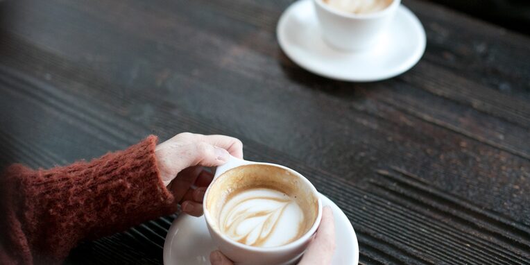 Kaffeetasse steht vor einer Frau