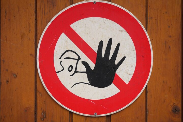 rundes rot weißes Warnschild mit einem Gesicht und einer Hand