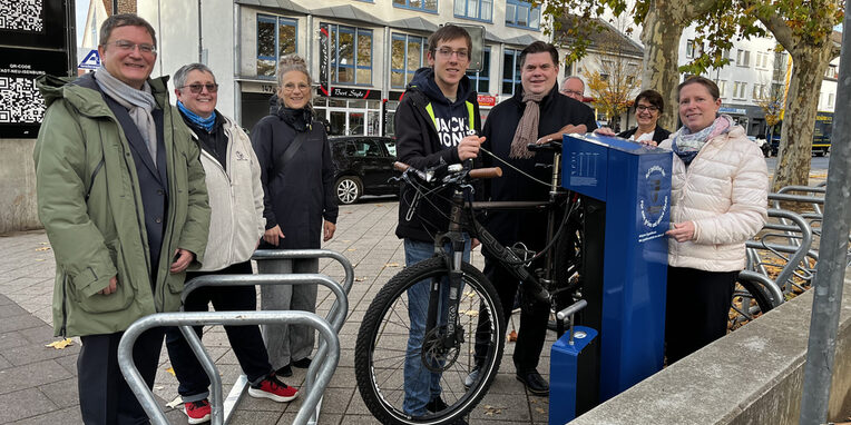 Rad-Reparaturstation und ein Element der mobilen Fahrradständer. Vlnr: Bürgermeister Dirk Gene Hagelstein, Yvonne Lammersdorf, Beauftragte Nahmobilität, Karin Rohde, Fahr-radkoordinatorin, Christian Adam, Jugendforum, Erster Stadtrat Stefan Schmitt, Stadtver-ordnetenvorsteherin Christine Wagner. Im Hintergrund vlnr: David Cappel, Fachbereichs-leitung Stadtbibliothek und Katja Harjes, stellvertretende Fachbereichsleitung Stadtbibliothek.
