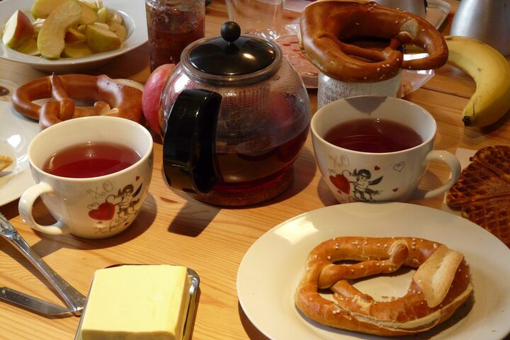 ein gedeckter Frühstückstisch mit Butter, Brezeln und Tee