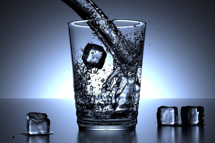Ein Glas, dass symbolisch mit Wasser und Eiswürfeln gefüllt wird