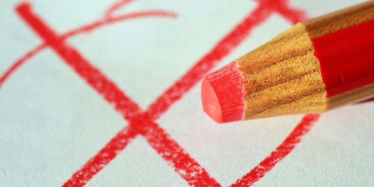 Roter Buntstift malt rotes X im Kreis