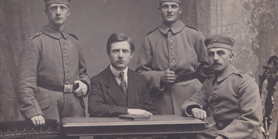 Ludwig Arnoul (links stehend in Uniform hinter seinem älteren Bruder Wilhelm in Zivil, sitzend am Tisch; die beiden anderen Soldaten sind unbekannt)