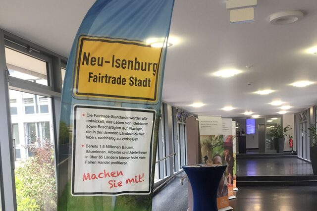 Fahne mit "Neu-Isenburg Fairtrade Stadt" steht im Foyer des Rathauses