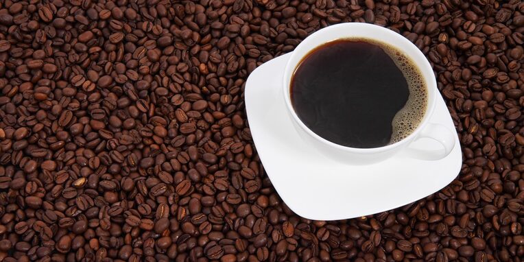 Tasse Kaffee steht auf Kaffeebohnen